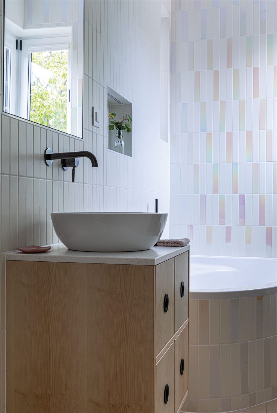 Bathroom with iridescent pastel tiles, vessel sink, and wooden vanity