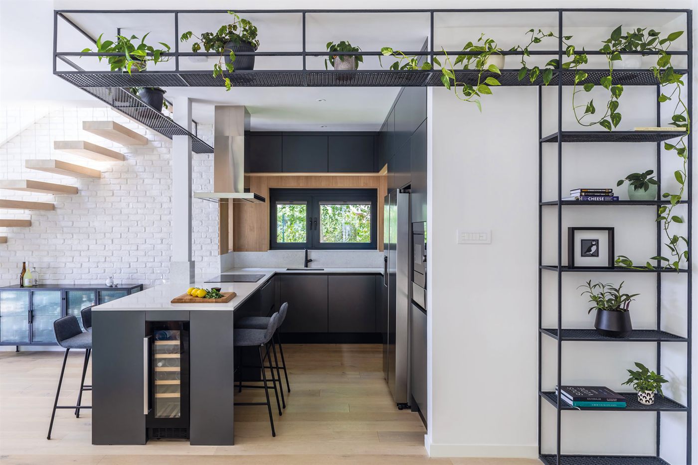 Kitchen with cantilevered staircase, metal shelving, and trailing plants