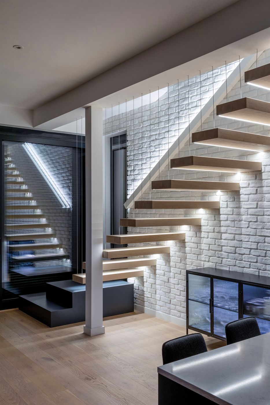 Cantilevered staircase with LED underlighting and white brick wall