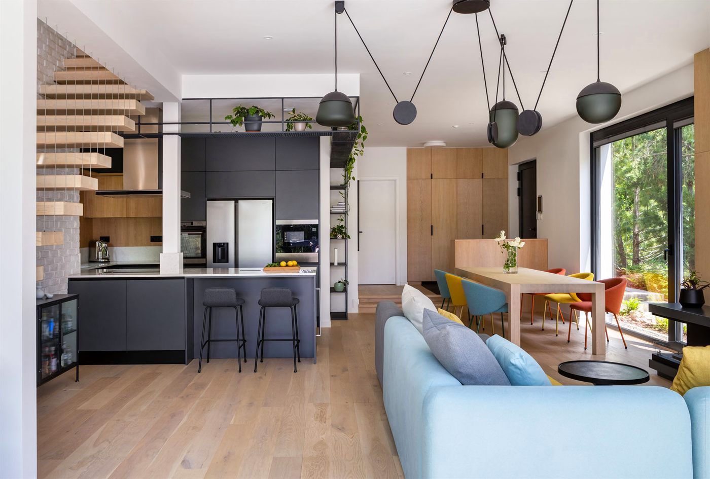 Open-plan kitchen, dining, and living area with blue sofa and colourful dining chairs