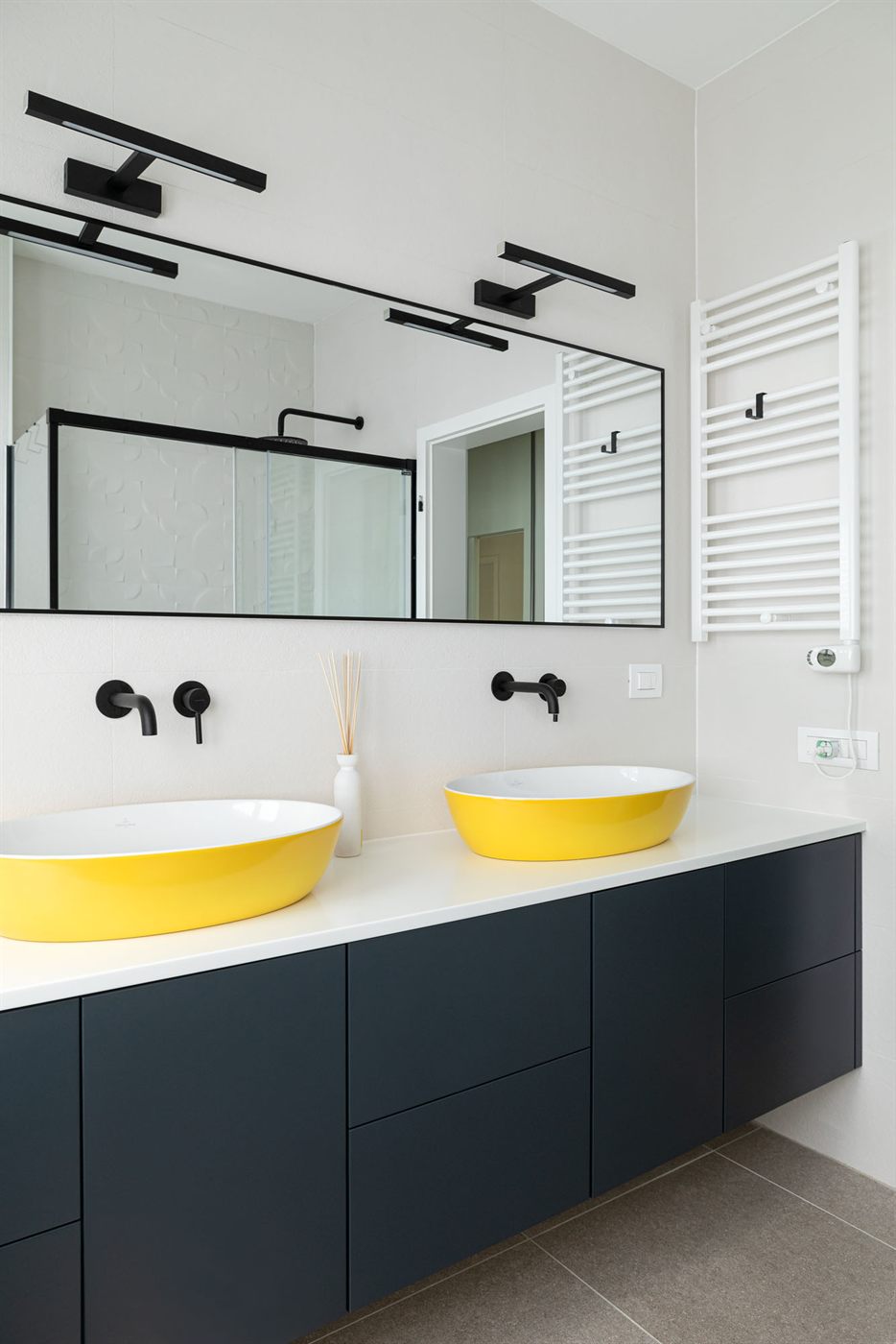 Bathroom with yellow vessel sinks, dark vanity, and large mirror