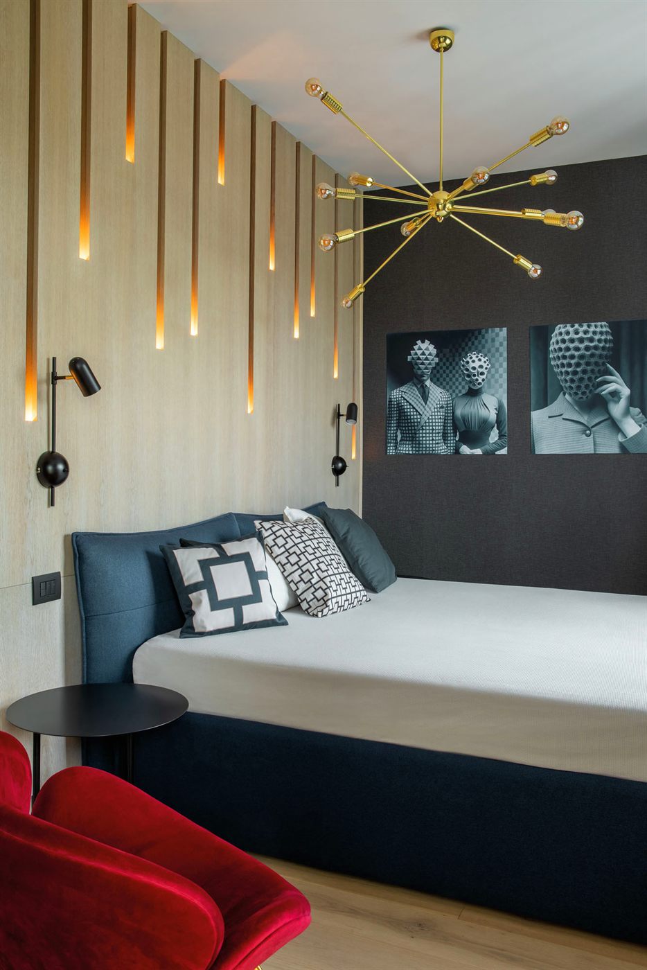 Master bedroom with sputnik chandelier, red velvet chair, and art photography